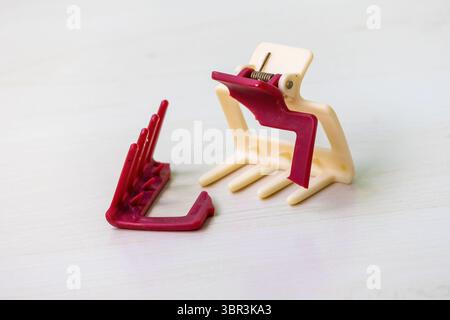 Fermaglio rotto sulla superficie in legno con parti danneggiate. Accessorio per capelli da donna danneggiato, noto anche come morsetto per capelli o clip per capelli. Foto Stock
