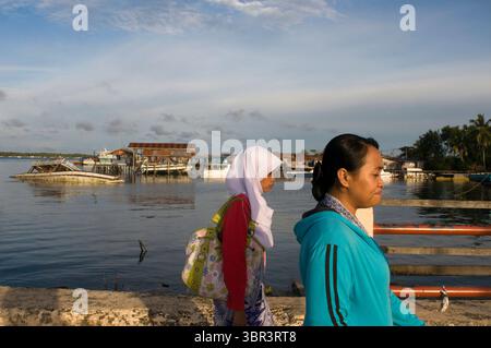 6 aprile 2010, Semporna, Borneo, Malesia: Porto di Senporna nel parco marino Tun Sakaran, Sabah, Borneo, Malesia orientale. Due donne locali camminano lungo il molo di Semporna. SLA Sipadan: L'isola di Sipadan è l'unica isola oceanica dell'arcipelago malese. Ha un paesaggio unico in quanto non condivide la solita strada dalle spiagge dell'arcipelago; ma è, come suggerisce la figura, un fungo che sporge dall'acqua. L'isola può ospitare solo 160 persone; ma dall'inizio di quest'anno è assolutamente vietato soggiornare in essa. È consentito solo al momento; immersioni. Tuttavia, in 15 o 20 minuti, è possibile Foto Stock