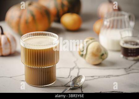 Latte di zucca speziato in una tazza di vetro con cannella e creem Foto Stock