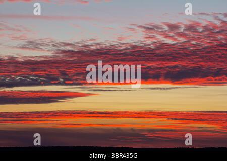 Uno splendido tramonto dipinge l'orizzonte con vibranti sfumature di rosso e arancione, creando una vista serena e pittoresca in una tranquilla posizione all'aperto. Foto Stock