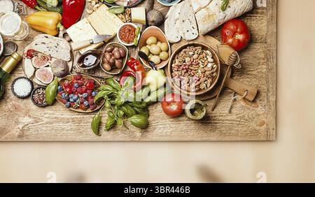 Tavolo con vista dall'alto pieno di cibo. Antipasti italiani e spuntini con vino. Varietà di formaggi, noci, olive mediterranee, salse, prosciutto e frutti di bosco Foto Stock