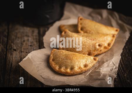 Tradizionali empanadas spagnole al forno con ripieno di carne o verdure su fondo di legno, fresche e fatte in casa. Cibo latino Foto Stock