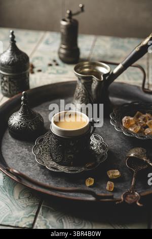 Caffè in metallo turco tradizionale tazza e caffè in chicchi su sfondo piastrellato Foto Stock