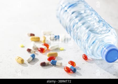 Pillole farmaceutiche assortite, compresse e capsule con acqua su fondo bianco Foto Stock