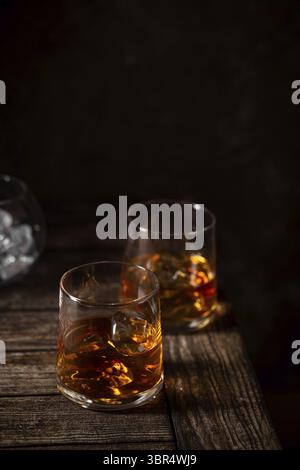 Due bicchieri di whisky con ghiaccio isolato su a. sfondo scuro Foto Stock