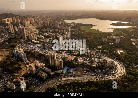 Vista aerea della fitta espansione urbana accostata al verde lussureggiante e al tranquillo lago Powai sotto la luce dorata del sole che tramonta, Powai, Mumbai, Foto Stock