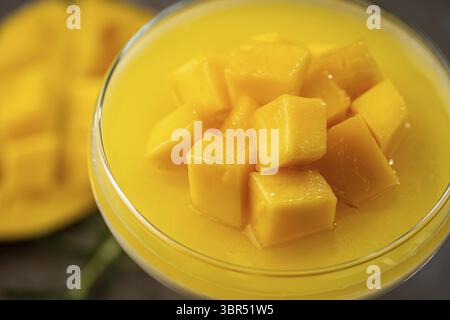 Panna cotta da dessert italiana con mango in vetro su sfondo grigio Foto Stock