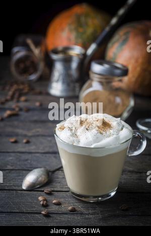 Latte di zucca con panna montata e spezie, con zucche sopra la consistenza del legno. Copia spazio Foto Stock