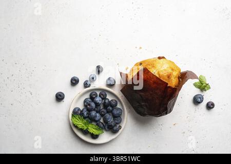 Muffin con dolci dolci fatti in casa con mirtilli e frutti di bosco freschi su sfondo bianco, vista dall'alto Foto Stock