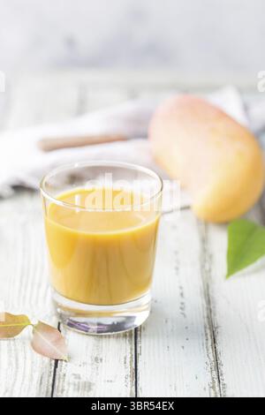 Frullato tropicale di mango in un bicchiere e mango fresco su sfondo chiaro. Mango Shake. Concetto di frutta tropicale Foto Stock