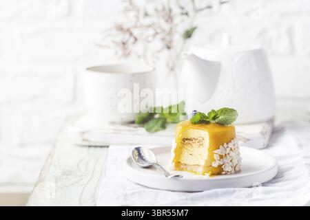 Fetta di mousse di mango sul piatto sopra un tavolo di legno bianco Foto Stock