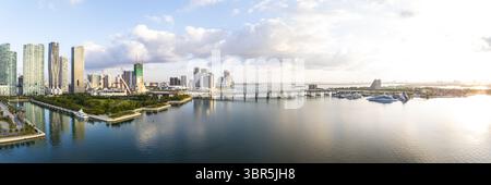 Vista aerea di grattacieli e ponti scintillanti che si riflettono nell'acqua, con il sole che sorge sul paesaggio urbano, Miami, Florida, Stati Uniti. Foto Stock