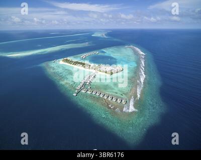 Vista aerea di uno splendido resort isolano con bungalow sull'acqua annidati in acque turchesi, circondati dal mare blu profondo, Malé e Maldive. Foto Stock
