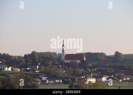 HAAG A OBERBAYERN, GERMANIA - 29 APRILE 2025: Vista mattutina dell'Haag con la chiesa di San Vito e i tetti del villaggio circostante illuminati dalla luce soffusa del sole Foto Stock