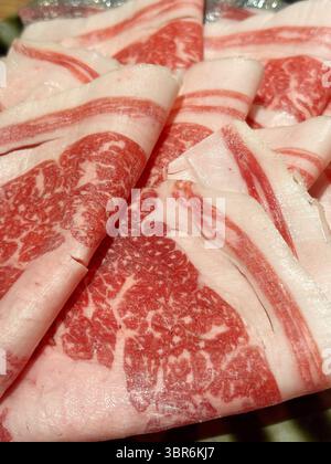 Primo piano di manzo crudo a fette sottili, pronto per essere utilizzato in shabu-shabu, sukiyaki o hot pot. Foto Stock