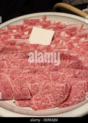 Un piatto con carne cruda a fette sottili, pronto per essere utilizzato in shabu-shabu, sukiyaki o hot pot. Foto Stock