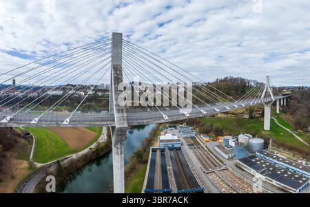 Veduta aerea dell'alto ponte Pont de la Poya sul tortuoso fiume, giustapposto agli edifici industriali e al lontano skyline della città, p. Foto Stock
