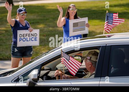 8 agosto 2020, West Des Moines, Iowa, Stati Uniti: People line Mills Civic Parkway di fronte alla stazione di polizia di West Des Moines e tifo come automobilista che sventola bandiere americane schiaccia a sostegno di loro durante una manifestazione a sostegno della polizia e delle forze dell'ordine. Circa 100 persone si sono riunite al West Des Moines Law Enforcement Center per radunarsi a sostegno delle forze dell'ordine. Il raduno è stato organizzato da "Uplifting Our Police", un'organizzazione locale che sostiene le forze dell'ordine. Si sono riuniti alla sede della polizia di Des Moines a luglio. Stanno pianificando manifestazioni simili nelle stazioni di polizia della metropolitana di Des Moines Foto Stock