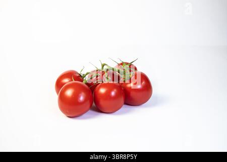 Sei pomodori freschi maturati in vite su sfondo bianco, che mostrano il loro vivace colore rosso e i gambi verdi, perfetti per cucinare, insalate o mangiare sano Foto Stock