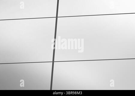 La facciata a parete in vetro dal design piatto è caratterizzata da pannelli riflettenti e griglia di mullion in metallo scuro Foto Stock