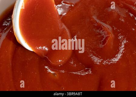 Macro di ketchup in Spoon. Primo piano con salsa rossa naturale. Foto Stock
