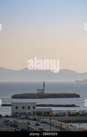 Vista costiera al tramonto con faro e skyline della città a Trapani, Sicilia Foto Stock