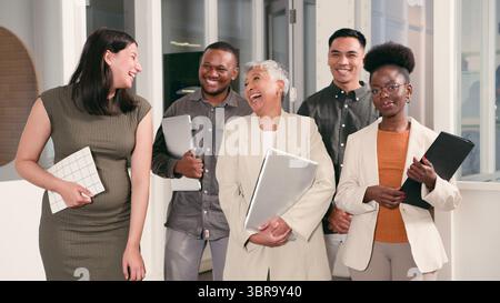 Gruppo diversificato di professionisti che collaborano e sorridono in un moderno ambiente d'ufficio Foto Stock