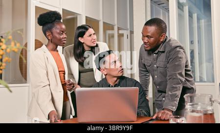 Collaborazione tra team intorno a un notebook in un ambiente di ufficio moderno Foto Stock