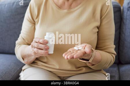 Anziana donna mani tenendo barattolo di pillole andare a prendere preparazioni mediche a casa Foto Stock