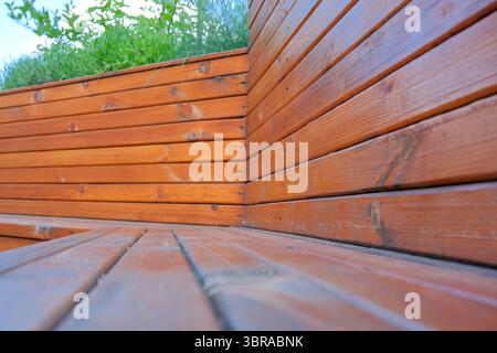 Una panca in legno serena incontra il verde fresco, invitante relax in un giardino tranquillo. Foto Stock