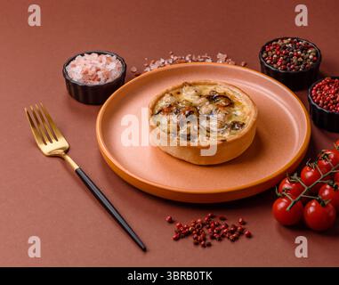 Torta o quiche, una crostata acida con pollo e funghi, spezie ed erbe aromatiche su sfondo di cemento scuro. Quiche rotonde con pollo Foto Stock