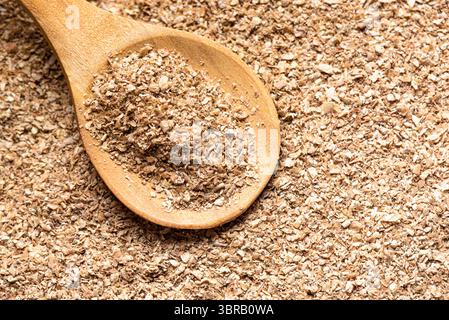 Fibra di crusca di frumento su cucchiaio di legno, primo piano, spazio copia. Struttura dettagliata di vari prodotti di crusca istantanea vegetale. Mangiare sano. Foto Stock