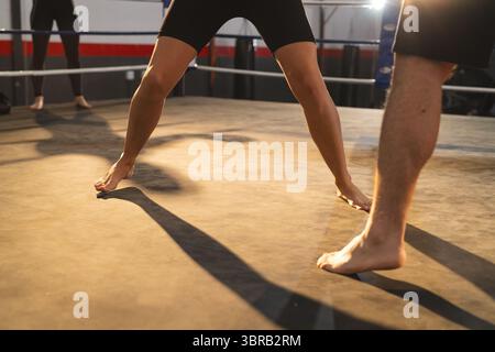 I partner per l'allenamento di pugilato giocano in un anello di pugilato con corde su tela che indossano pantaloncini corti e leggings Foto Stock