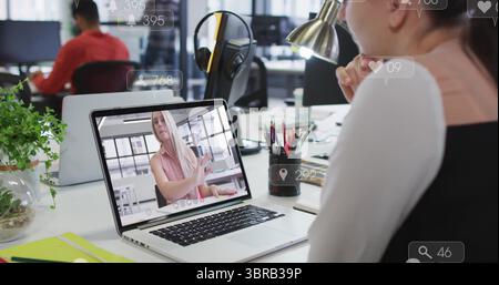 Visualizzazione di un collega remoto sullo schermo di un notebook, di un lavoratore che indossa un abito nero in ufficio, di uno spazio per le copie Foto Stock
