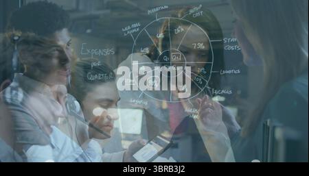 Professionisti che collaborano intorno a lavagna di vetro in ufficio, con grafico a torta, tablet e cuffie Foto Stock