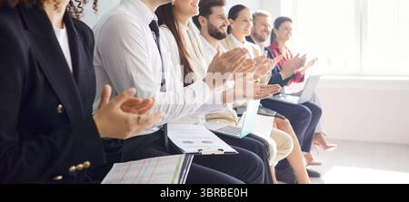 Gli uomini d'affari applaudono nella sala conferenze durante la riunione, celebrando un evento aziendale di successo. Foto Stock