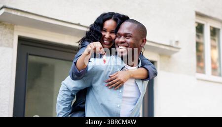 La coppia di sposi festeggia l'acquisto di First Home, tenendo in mano le chiavi lucenti. Foto Stock