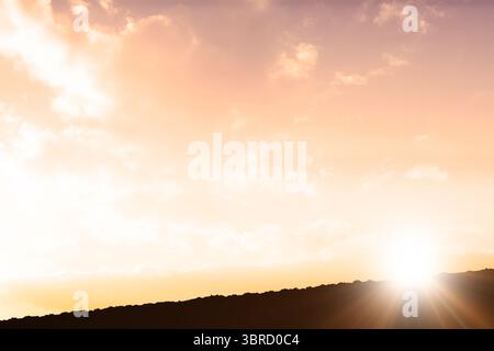 Il sole sorge sopra la silhouette del crinale con un design piatto, diffondendo raggi luminosi attraverso nuvole sparse Foto Stock
