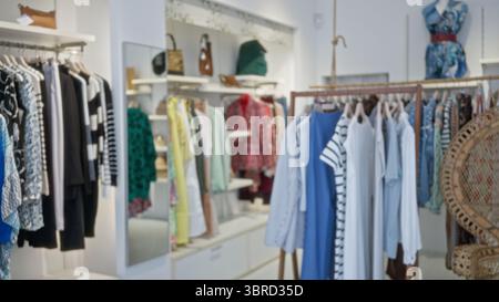 Il negozio di abbigliamento interno offre una vista sfocata di abiti colorati e capi appesi su scaffali, creando una vivace scena di shopping sfocato con un aspetto polveroso Foto Stock