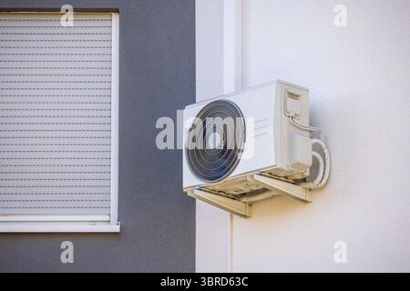 Condizionatore d'aria e pompa di calore installati su un muro di una casa di famiglia, unità con sistema diviso Foto Stock