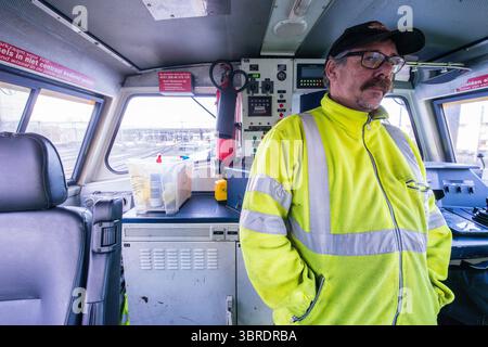 Autista maschio, medio adulto e autista di treno di un treno di supporto diesel, che supporta un grande lavoro di revisione sui binari del treno da parte di un subappaltatore dell'organizzazione ProRail presso il Willemspoor Tunnel di Rotterdam, Paesi Bassi. Foto Stock