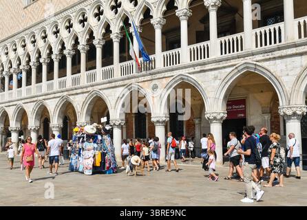 Turisti di fronte al Palazzo Ducale, con un chiosco di souvenir sul lungomare di Riva degli Schiavoni, in estate, Venezia, Veneto, Italia Foto Stock
