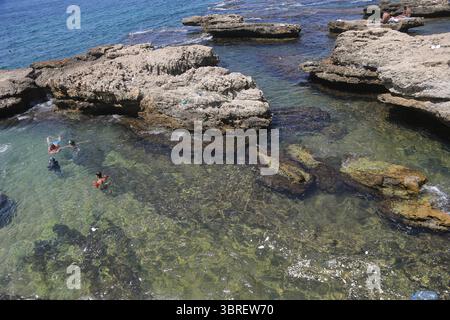 12 luglio 2025, Beirut, Beirut, Libano: Una famiglia libanese nuota in mezzo alla spazzatura vicino a uno sbocco di acque reflue nell'area di Manara a Beirut, una zona altamente inquinata secondo quanto valutato dal Consiglio nazionale per la ricerca scientifica (CNRS). Le analisi confermano che le concentrazioni di metalli pesanti rimangono ben al di sotto dei limiti di sicurezza internazionali, affermando che i pesci catturati localmente sono ancora sicuri per il consumo. Tuttavia, l'inquinamento da plastica continua a rappresentare una minaccia grave e crescente. I libanesi più poveri hanno poche buone scelte per godersi la spiaggia nella sfarzosa estate mediorientale. Percorri l'autostrada costiera e il sig Foto Stock