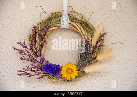 La corona fatta a mano presenta un assortimento di fiori secchi, tra cui girasoli, lavanda e piume. Foto Stock