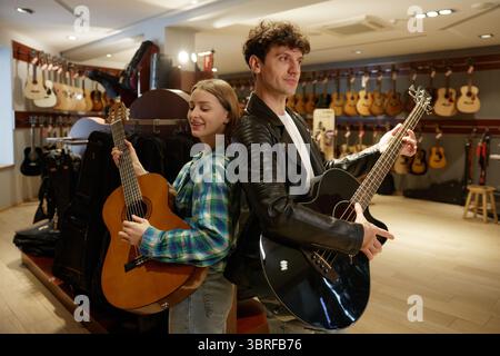 In un negozio di musica, un uomo e una donna suonano le loro chitarre abilmente Foto Stock
