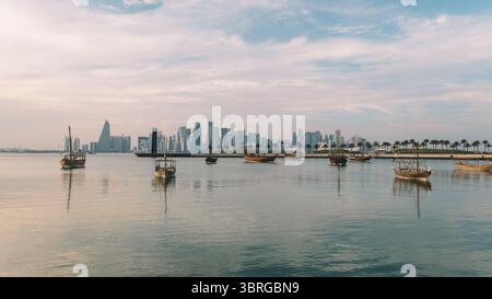 Una vista serale della Corniche a Doha, Qatar, in serata al tramonto. Barche tradizionali arabe in sambuco nel porto di Doha, Qatar Foto Stock