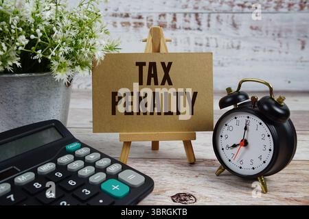 Testo della sanzione fiscale con sveglia e calcolatrice su sfondo in legno Foto Stock
