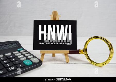 HNWI abbreviazione di High Net-Worth testo individuale con lente di ingrandimento e calcolatrice su sfondo in legno Foto Stock