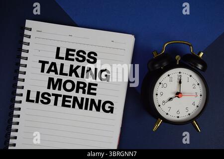 Meno chiacchiere più testo da ascoltare scritto sul blocco note con sveglia su sfondo blu navy Foto Stock