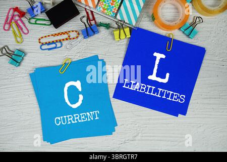 CL - testo delle passività correnti su stick note con cancelleria su sfondo concreto Foto Stock